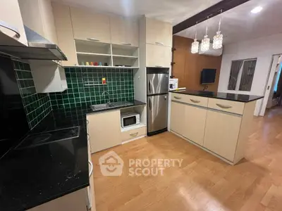Modern kitchen with open layout, stainless steel appliances, and stylish green tile backsplash.