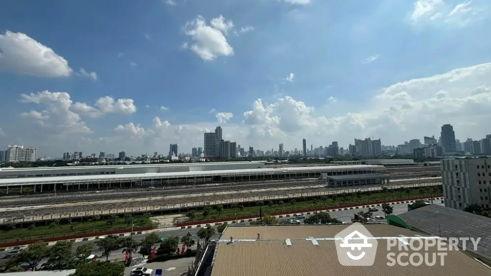 Stunning cityscape view from high-rise building showcasing urban skyline and railway tracks under blue sky.