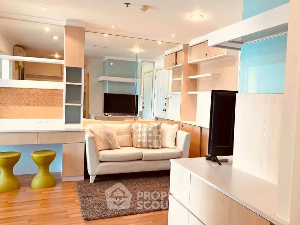Modern living room with stylish furniture and built-in shelves, featuring a cozy sofa and flat-screen TV.