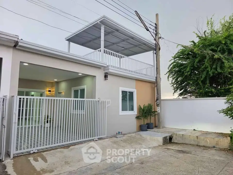 Modern two-story house with gated driveway and rooftop terrace