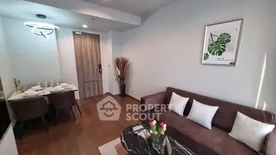 Modern living room with stylish decor and dining area, featuring elegant lighting and cozy seating.
