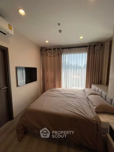 Cozy bedroom with modern decor and large window offering natural light.