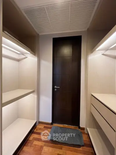 Spacious walk-in closet with wooden flooring and ample shelving.