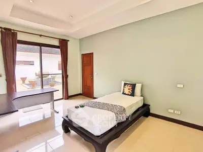 Spacious bedroom with modern decor and large window offering natural light and garden view.