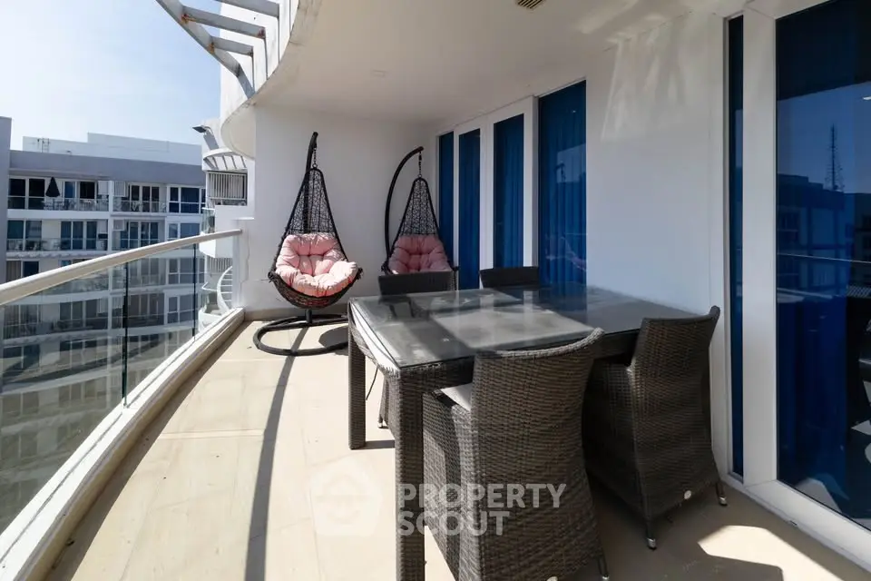 Spacious balcony with modern outdoor furniture and hanging chairs in a luxury apartment.
