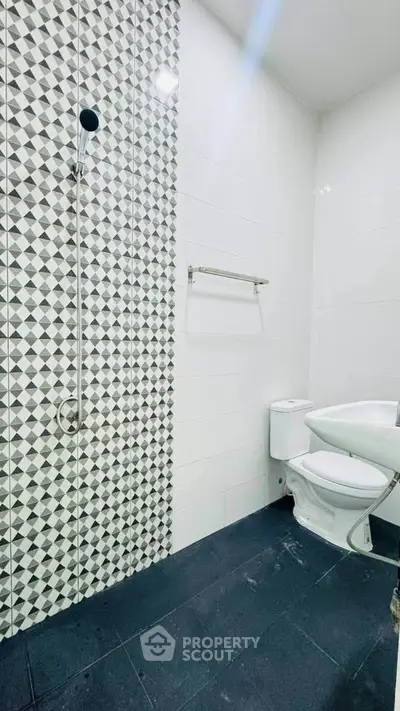 Modern bathroom with stylish geometric tile shower and sleek fixtures.