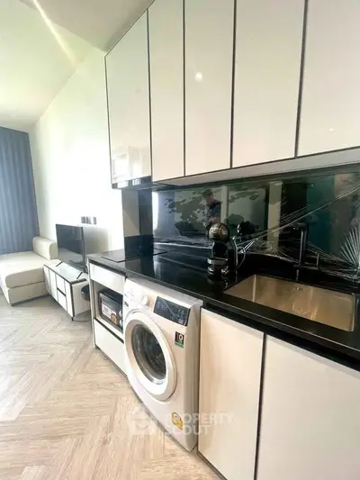 Modern kitchen with sleek cabinetry and built-in washing machine in stylish apartment.