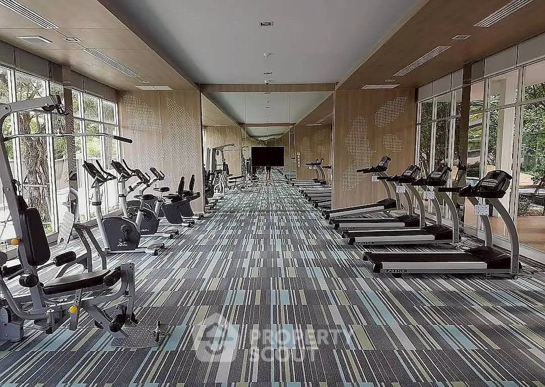 Spacious modern gym with state-of-the-art equipment and large windows offering natural light.
