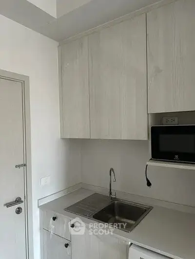 Modern compact kitchen with sleek cabinetry and built-in microwave