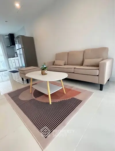 Modern living room with stylish beige sofa and chic coffee table on patterned rug.