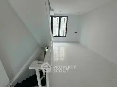 Bright white interior space with staircase and large window, ideal for modern living.
