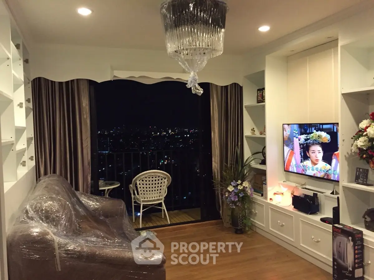 Cozy living room with balcony view, elegant chandelier, and modern decor.