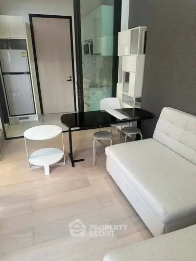 Modern living room with sleek furniture and open kitchen layout in a stylish apartment.