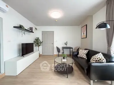 Modern living room with sleek black sofa, stylish decor, and natural light for a cozy ambiance.