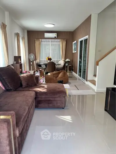 Spacious living room with modern decor and natural light, featuring a cozy sofa and dining area.