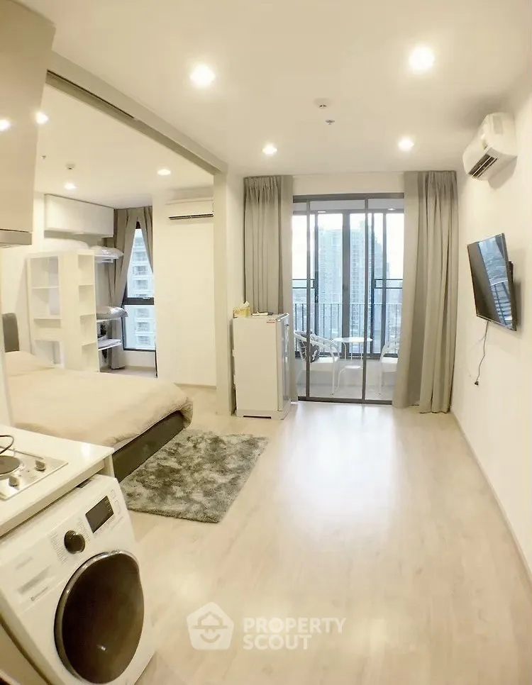 Modern studio apartment with open layout, featuring a cozy living area, compact kitchen, and balcony with city view.