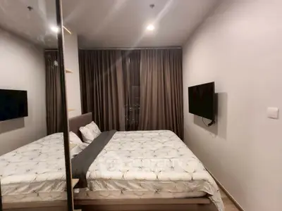 Cozy modern bedroom with mirrored closet and wall-mounted TV in stylish apartment.
