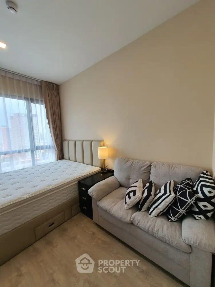 Cozy bedroom with stylish sofa and large window offering city views
