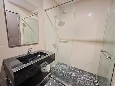 Modern bathroom with sleek black marble sink and glass shower enclosure