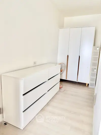Minimalist bedroom with sleek white furniture and ample storage space
