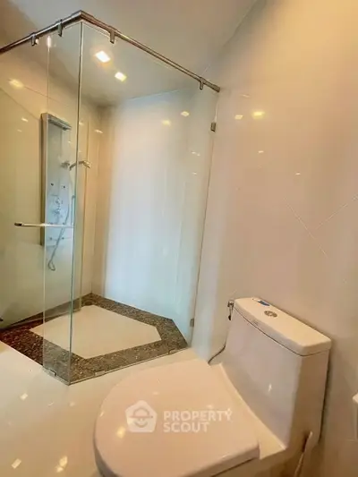 Modern bathroom with glass shower enclosure and sleek toilet design.