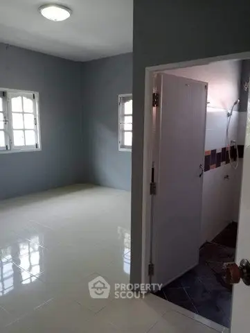 Spacious room with tiled flooring and adjacent bathroom in modern apartment.