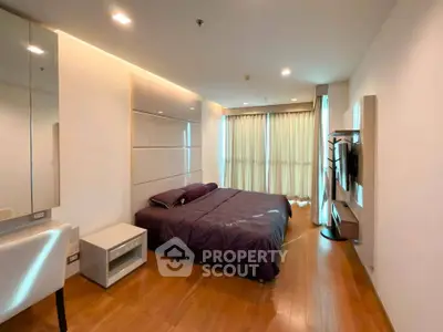 Spacious modern bedroom with wooden flooring and large windows in a luxury apartment.