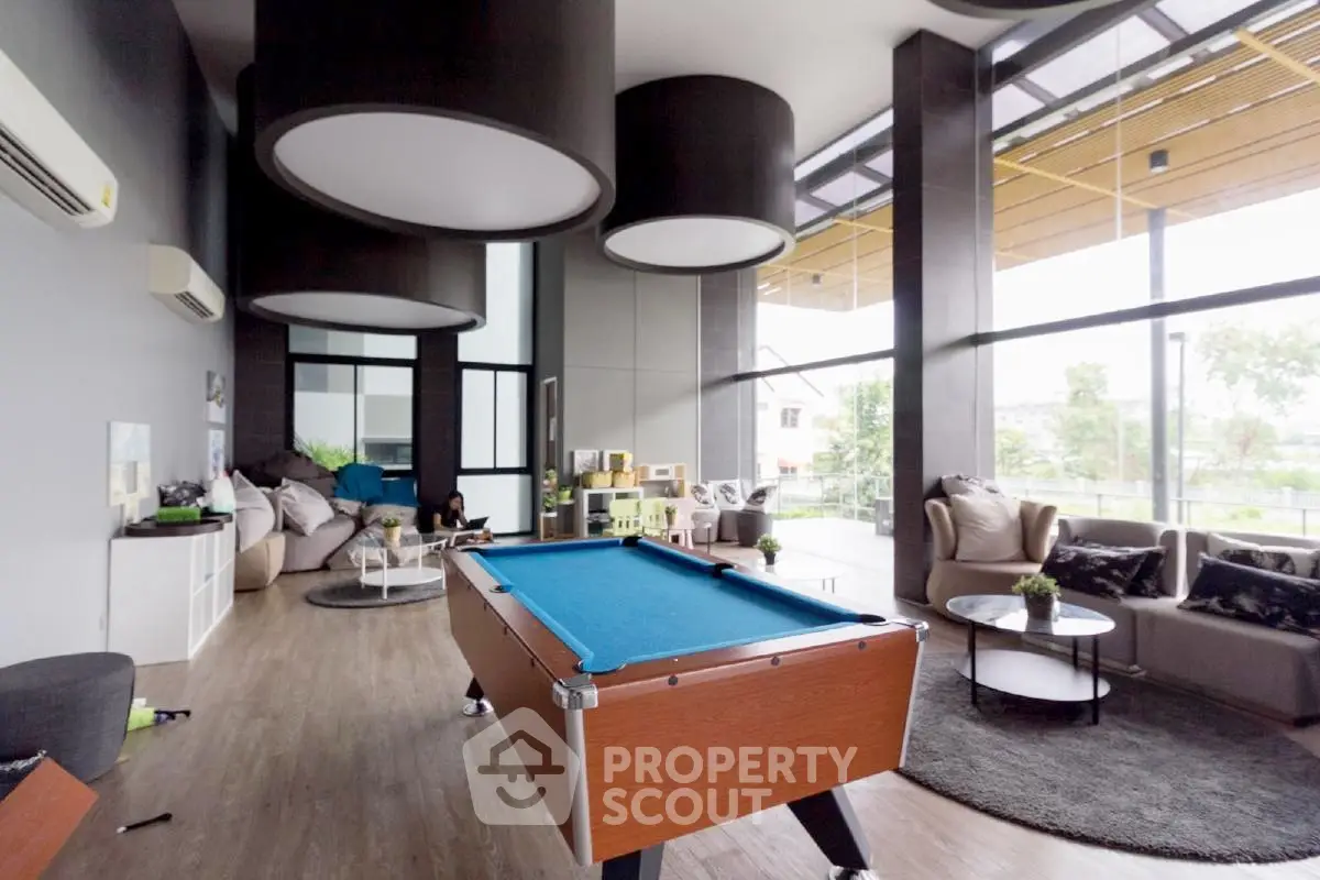 Spacious modern living room with pool table and large windows offering a scenic view.