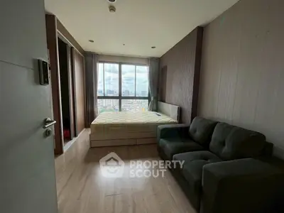 Modern bedroom with city view, featuring a cozy bed and stylish sofa, perfect for urban living.