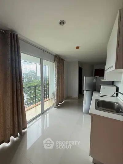 Modern kitchen with balcony view, sleek cabinetry, and natural light in a stylish apartment.