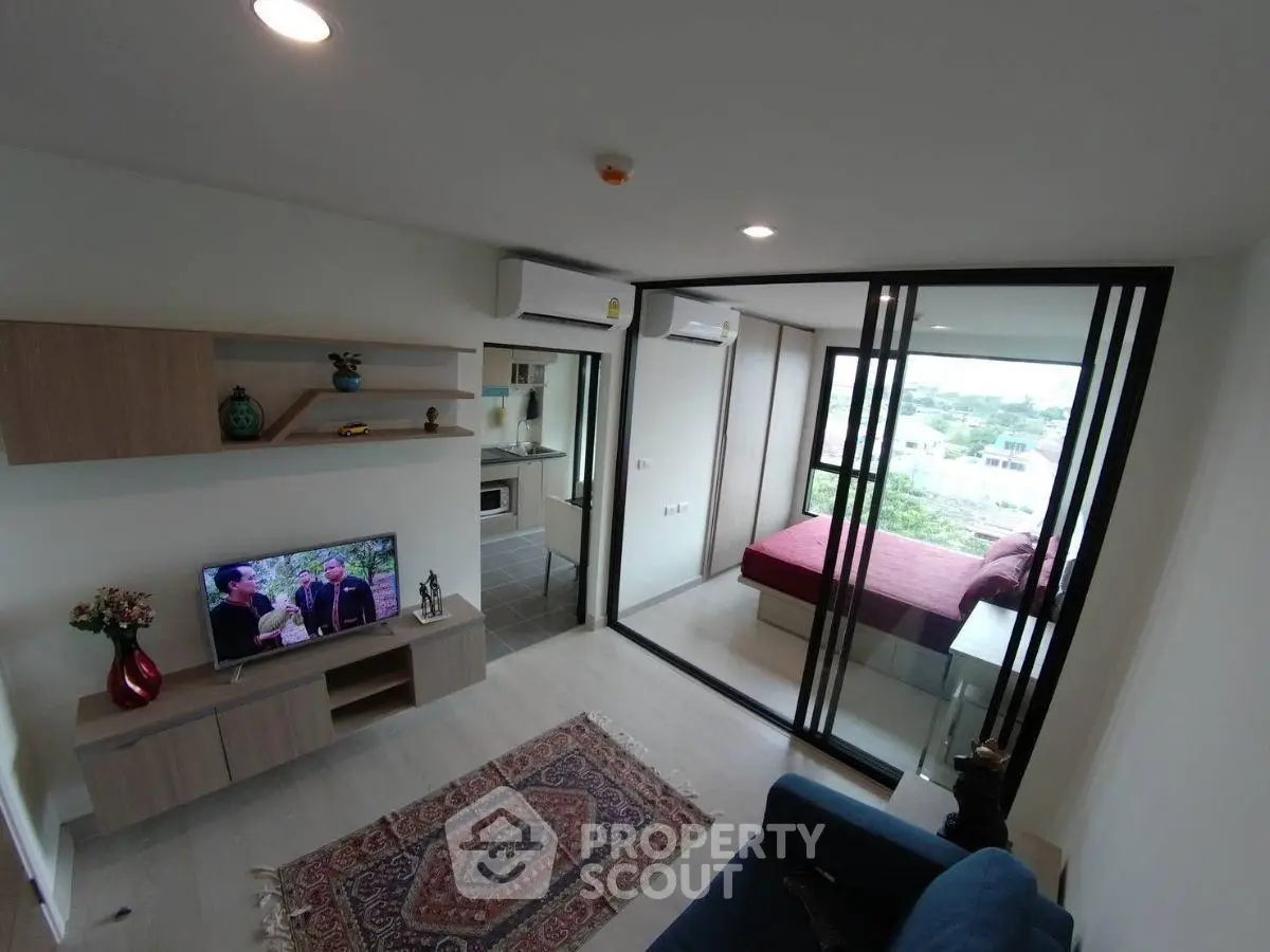 Modern living room with sliding glass doors leading to a bedroom, featuring stylish decor and a scenic view.