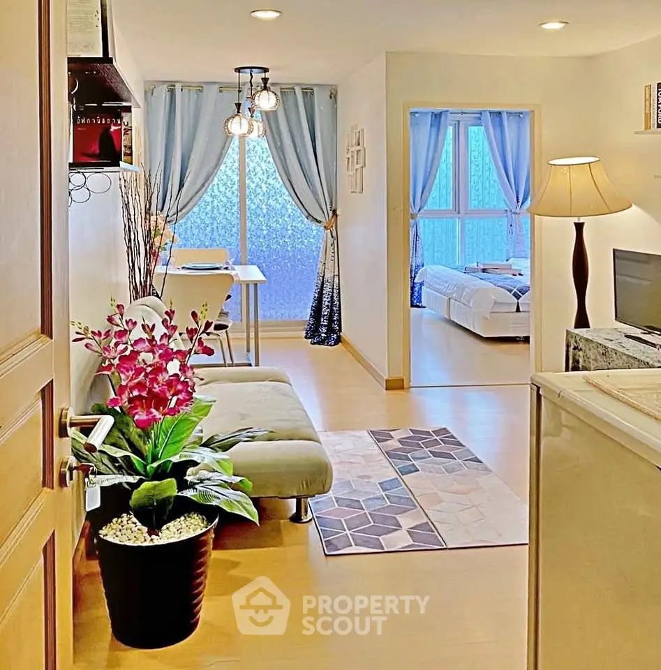 Charming open-plan living room with cozy decor and natural light, featuring a view into a stylish bedroom.
