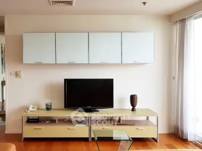Modern living room with sleek TV stand and wall-mounted cabinets, featuring elegant decor and natural light.