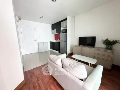 Modern living room with open kitchen, sleek furniture, and wooden flooring in a cozy apartment.