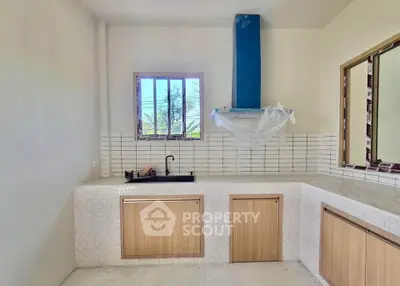 Modern kitchen with sleek cabinetry and tiled backsplash, featuring a unique blue range hood.
