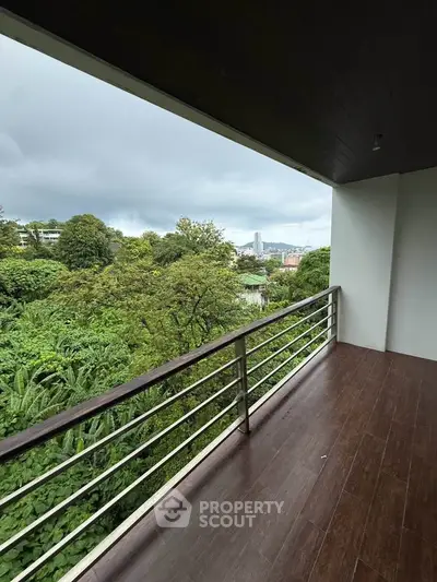 Spacious balcony with lush green view and city skyline in the distance.