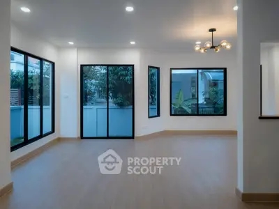 Spacious modern living room with large windows and elegant lighting, perfect for natural light and comfort.