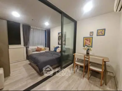 Modern studio apartment with glass partition, cozy bedroom, and stylish dining area.