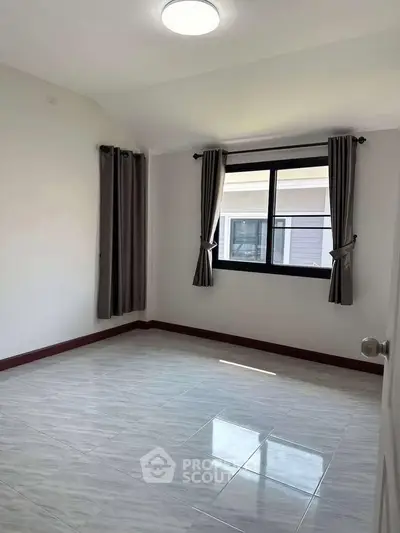 Spacious empty bedroom with large window and elegant curtains in modern home.