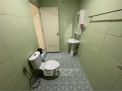 Spacious bathroom with green tiles and modern fixtures