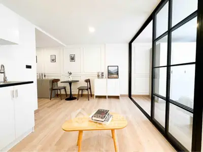 Modern living room with stylish decor and glass partition in a bright apartment.