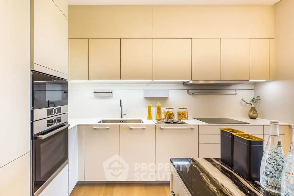 Modern kitchen with sleek cabinetry and built-in appliances, featuring a stylish black marble countertop.