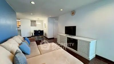 Spacious living room with modern decor and cozy seating in a stylish apartment.