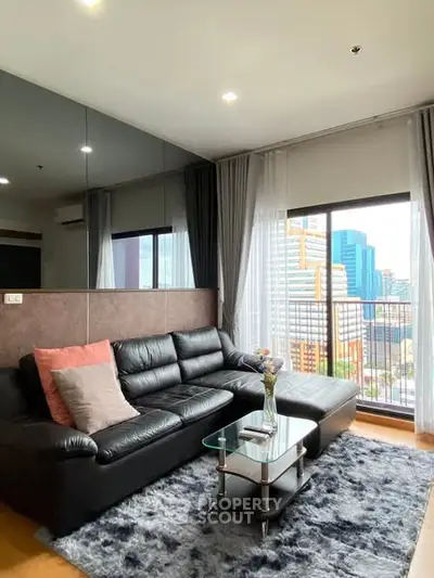 Modern living room with city view, black leather sofa, and stylish decor.