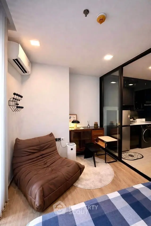 Modern living room with cozy seating and sleek kitchen area in open layout apartment.
