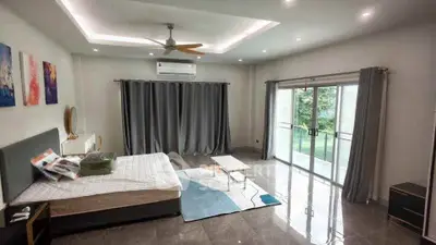 Spacious bedroom with large windows and modern decor, featuring a serene garden view.