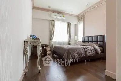 Elegant bedroom with hardwood floors, luxurious bed, and stylish decor in a modern apartment.