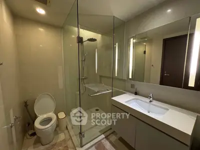 Modern bathroom with glass shower and sleek vanity in contemporary home.