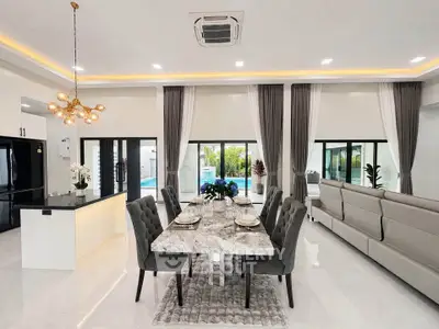 Luxurious open-plan living and dining area with elegant decor and pool view.