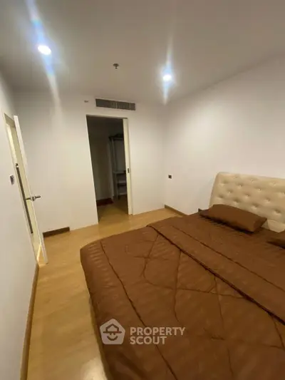 Cozy bedroom with modern decor and warm lighting, featuring a comfortable bed and wooden flooring.